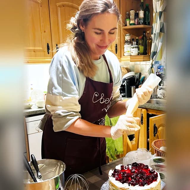Moodrise founder piping cream onto a layered cake in her kitchen